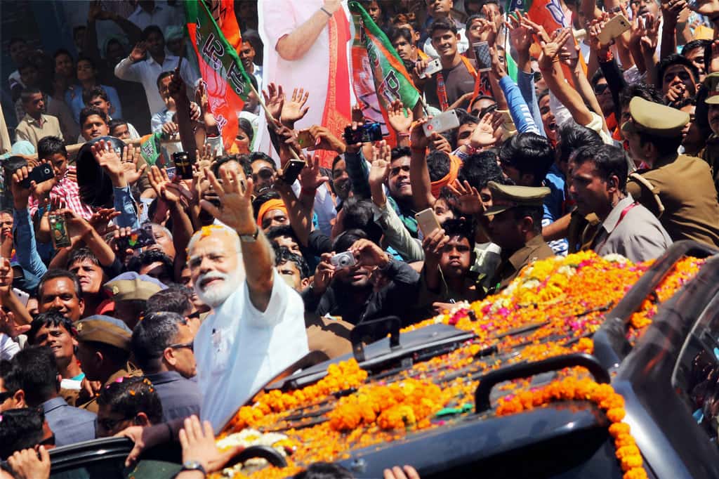 Prime Minister Narendra Modi waves at people at road show at Ramnagar. (Photo: PTI)
