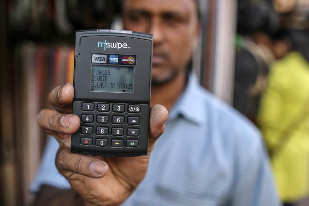 A vendor holds an Mswipe terminal, operated by M-Swipe Technologies Pvt Ltd., in an arranged photograph at a roadside stall in Bengaluru, India. (Photographer: Dhiraj Singh/Bloomberg)