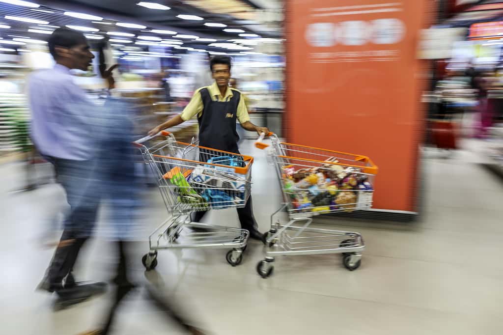 An employee pushes shopping carts (Photographer: Dhiraj Singh/Bloomberg)