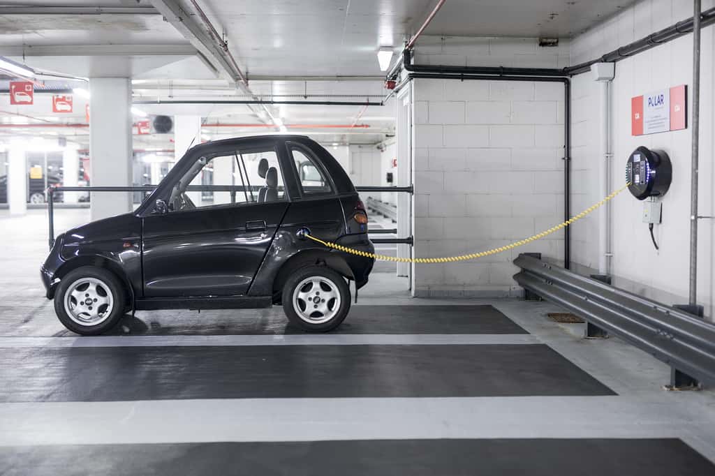 A charging plug connects an electric vehicle (EV) to a charging station at Q-Park Park Lane underground parking lot in London (Photographer: Simon Dawson/Bloomberg)